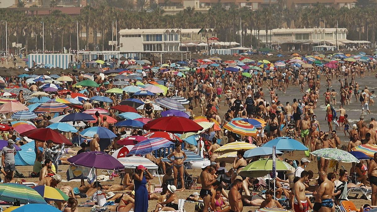 La playa de la Malva-rosa de València se llenó hasta los topes de gente que buscaba combatir el intenso calor. | FERNANDO BUSTAMANTE