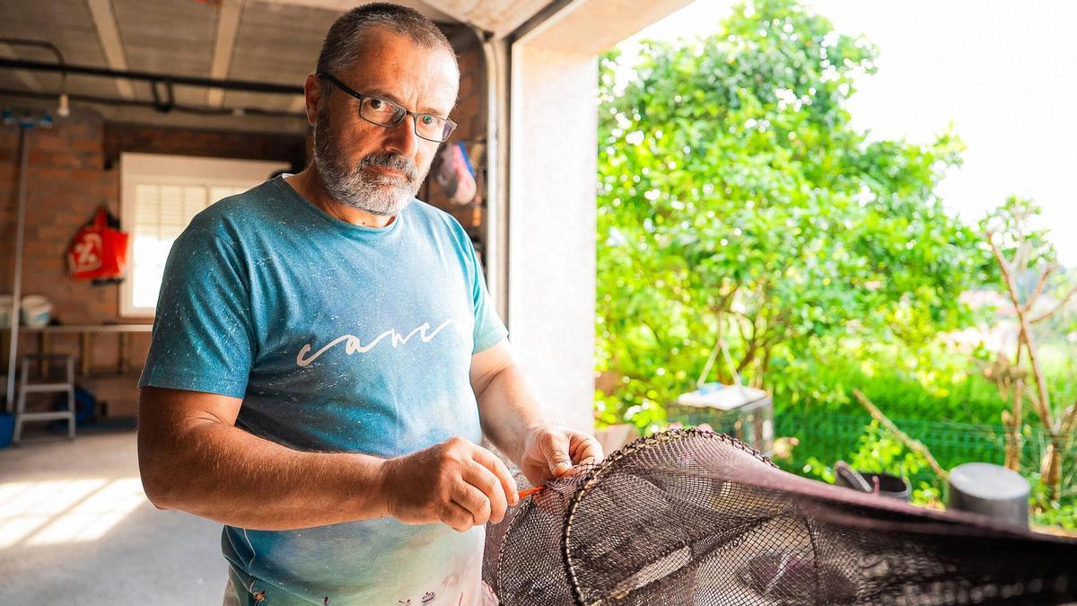 El anguilero Juan Carlos Rivas cose en su casa una de las nasas destrozadas por los arroaces.