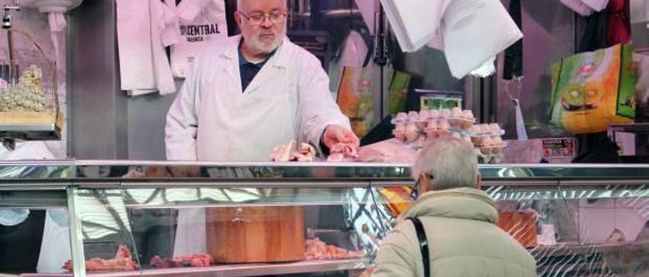 Fernando Gimeno atiende a una clienta en el puesto del Mercado Central.