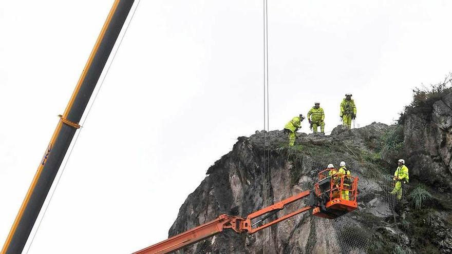 Los operarios, colocando ayer la malla de protección en la zona alta de la ladera.