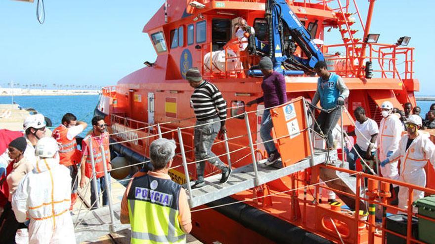 Un agente de la Policía Nacional supervisa la llegada de inmigrantes rescatados en alta mar.