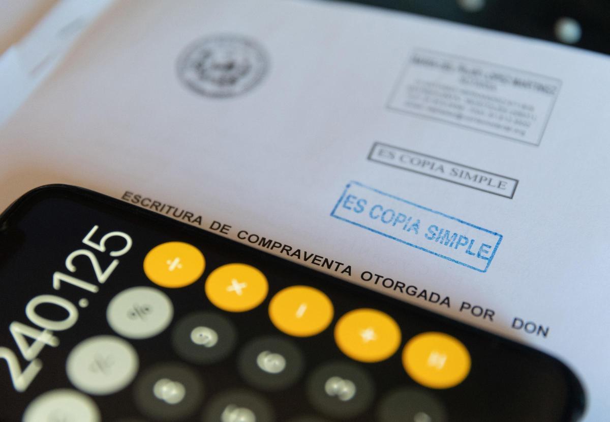 Una calculadora y una escritura de compraventa de una hipoteca
