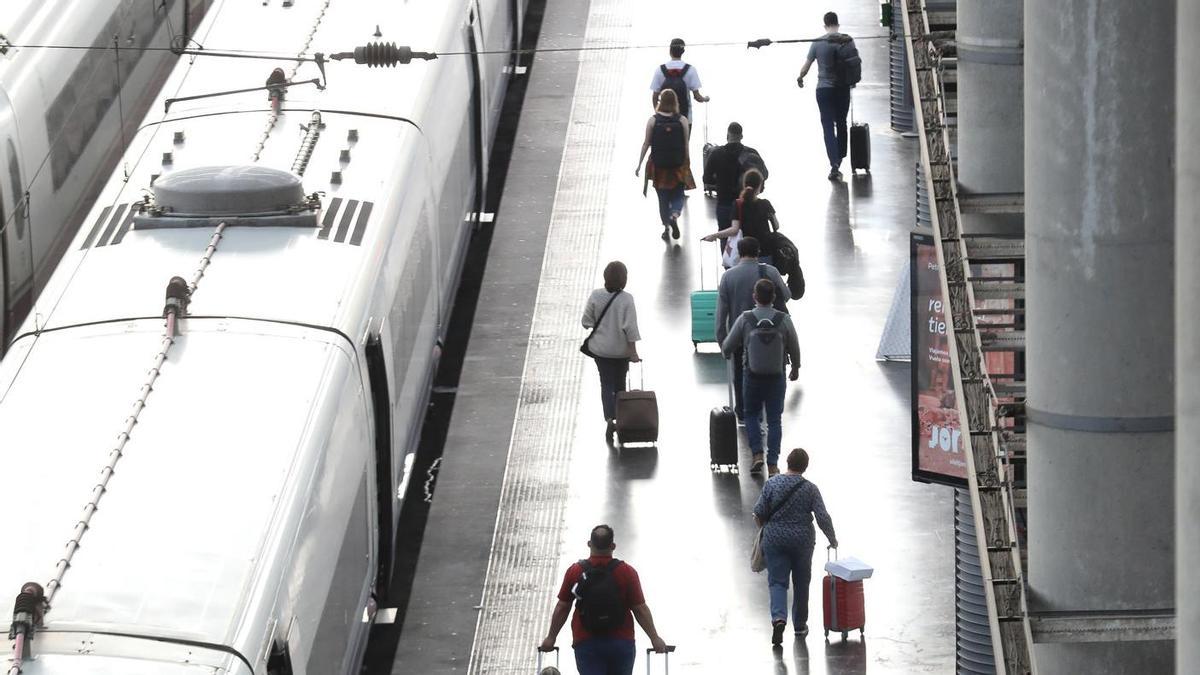 Varios pasajeros con maletas en el andén de un tren en la estación de Puerta de Atocha.