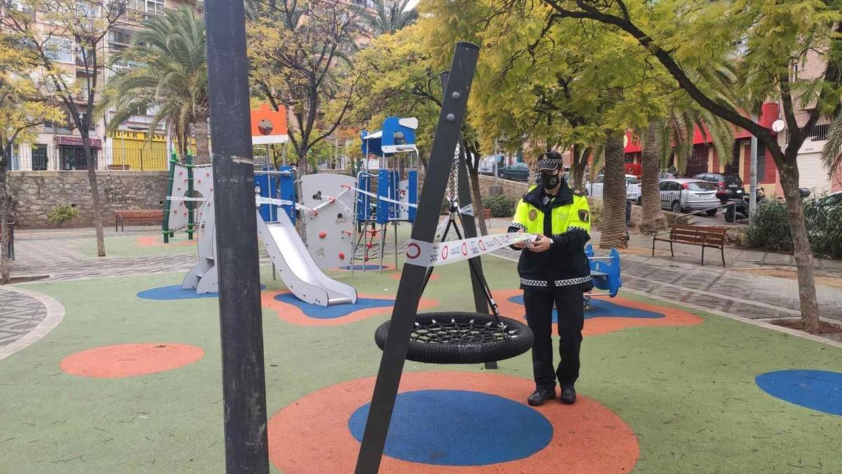 Un agente repone el precinto roto en un parque infantil