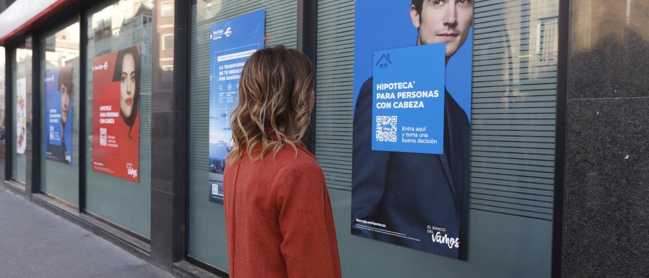 Una joven mira un anuncio de una entidad bancaria en Zaragoza.