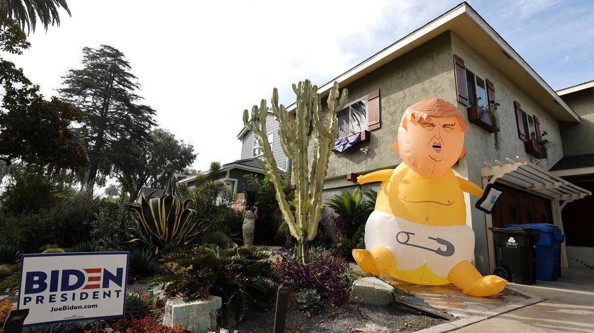 Un dirigible inflable gigante que representa al presidente Donald Trump, se ve en el jardín delantero de una casa con un cartel de Biden para presidente durante las elecciones presidenciales.
