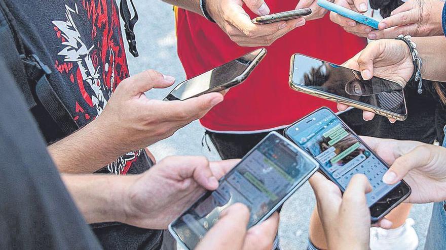 Un grupo de menores intercambia mensajes a través de una aplicación de sus teléfonos móviles.