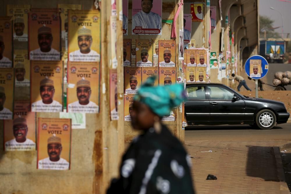 A woman walks past electoral campaign posters ...