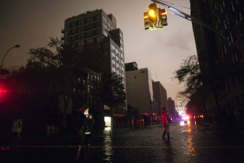 La gente toma fotos en una calle oscura inundada durante un apagón en Chelsea