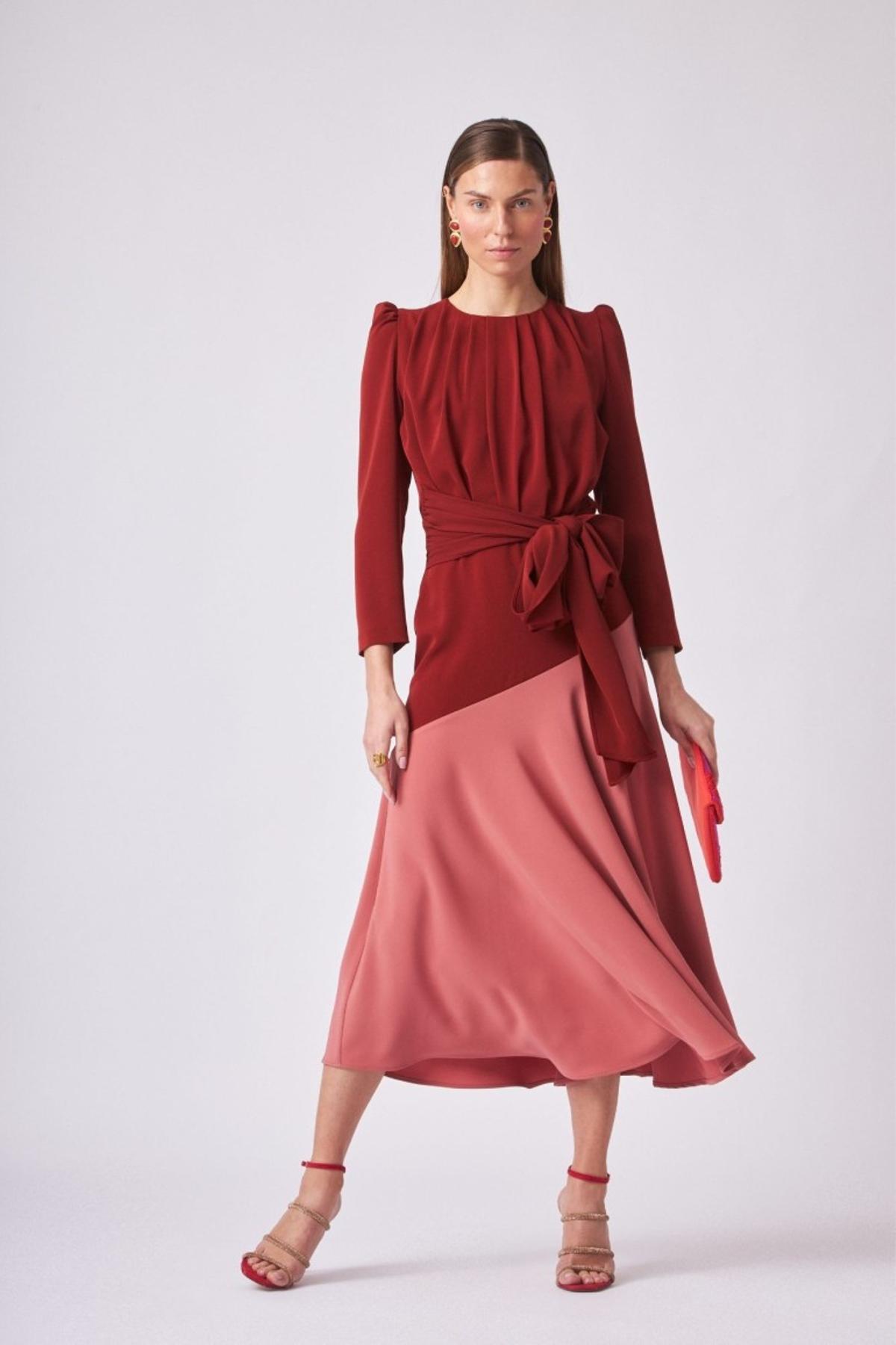 Vestido confeccionado en crepe bicolor rosa y granate de largo midi con volante asimétrico, escote redondo y manga larga abullonada.
