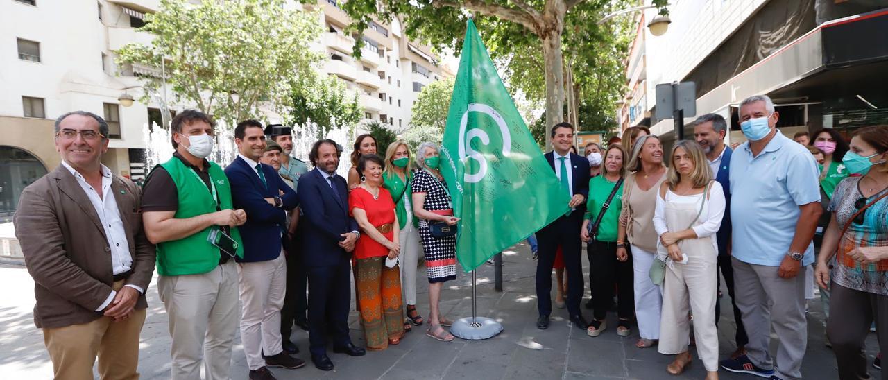 Autoridades y representantes de la Asociación Española Contra el Cáncer izan la bandera de la organización para visibilizar y recaudar fondos