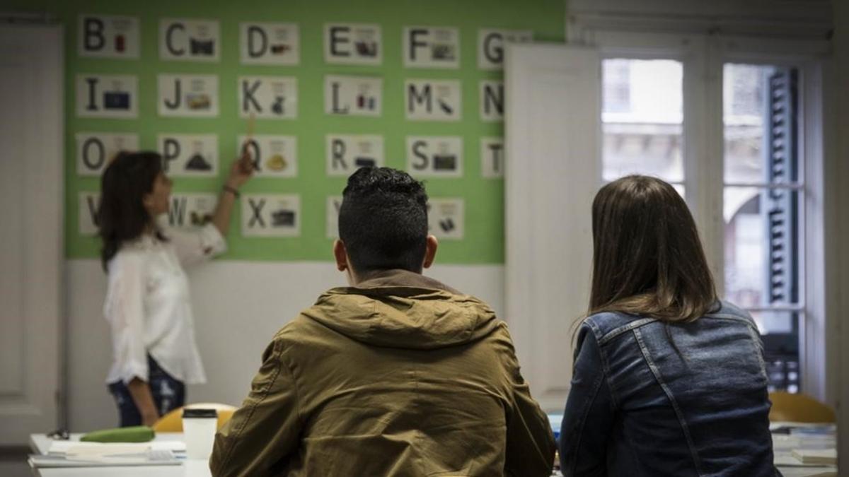 Mireia Escobar, coordinadora del proyecto de jovenes Ta-Axira, junto a un joven migrante y su profesora Constanza en una de las clases de castellano.