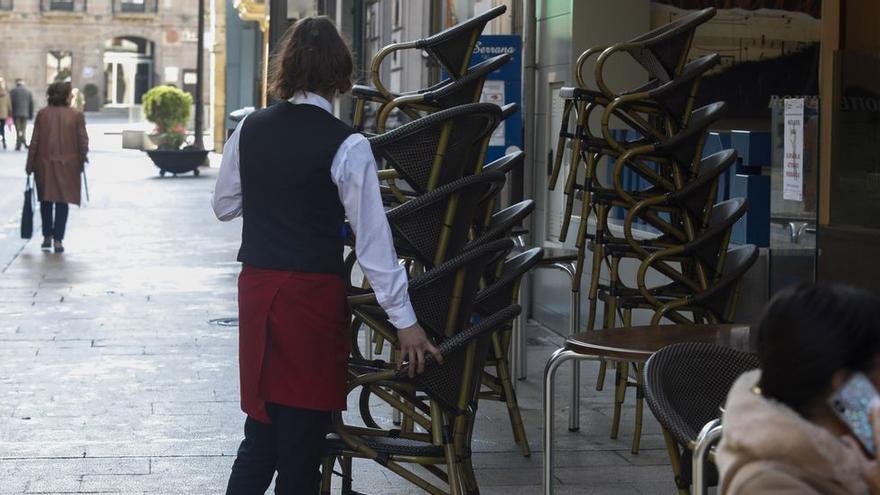 Una camarera coloca sillas en una terraza de Avilés. | MARA VILLAMUZA