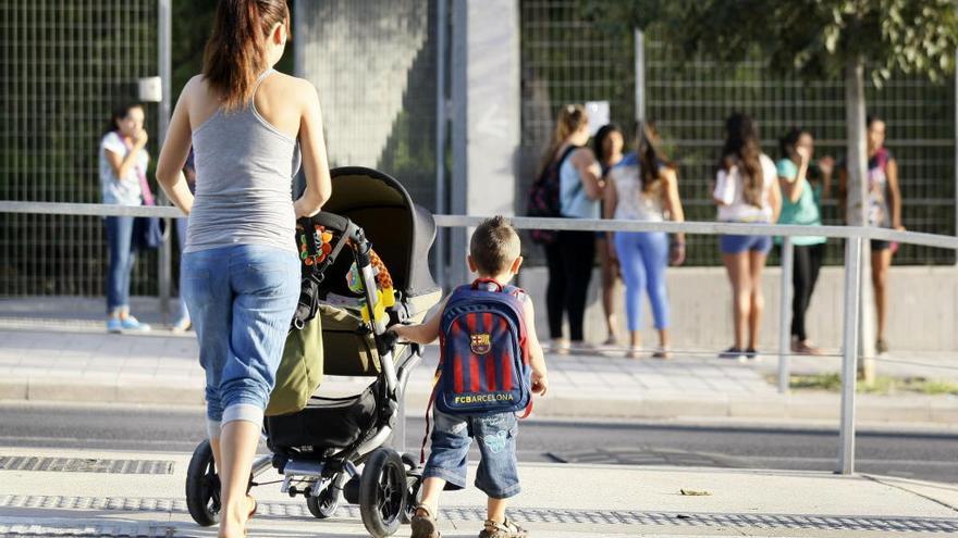 Una madre lleva a su hijo al colegio en el primer día de clase.