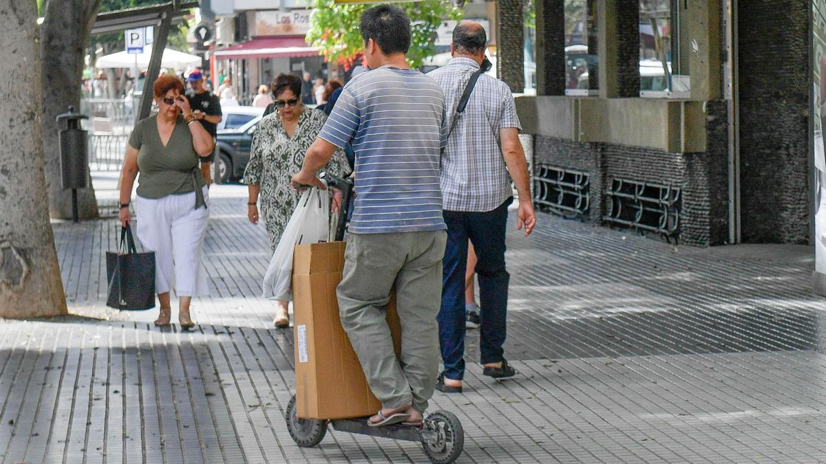 Un conductor en patineta por una acera de Mesa y López.