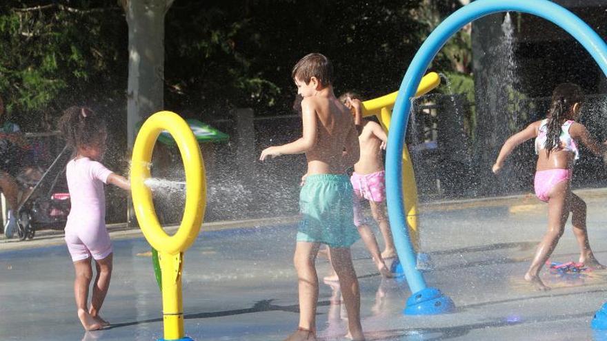 Varios menores en el parque infantil, de la alameda del Cruceiro, jugando con el agua.   | // IÑAKI OSORIO
