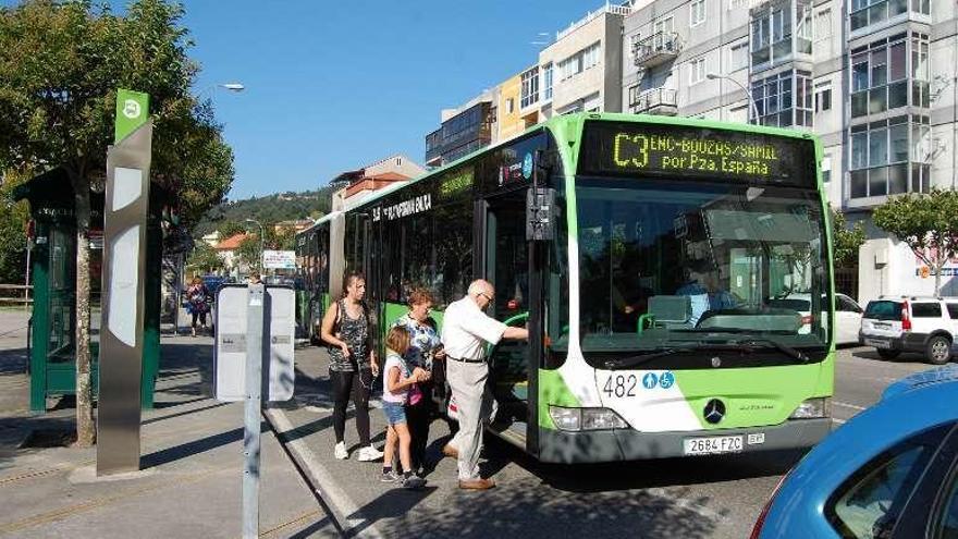 Pasajeros suben a un autobús de Vitrasa en la PO-323, en Chapela.