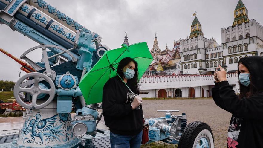 Dos mujeres con mascarilla se fotografían en Moscú.