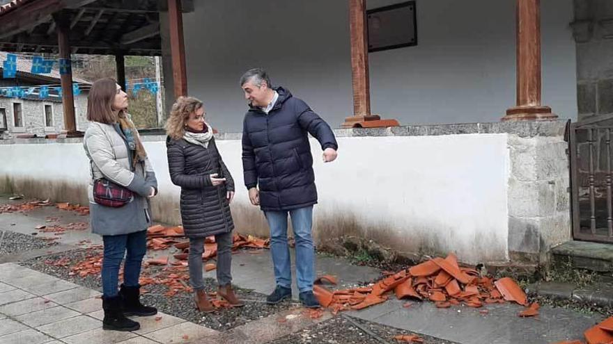 Susana Fernández, en el centro, junto a Paz García Benítez y Julián Bravo, durante la visita a la iglesia de Caleao, con tejas desprendidas en el suelo.