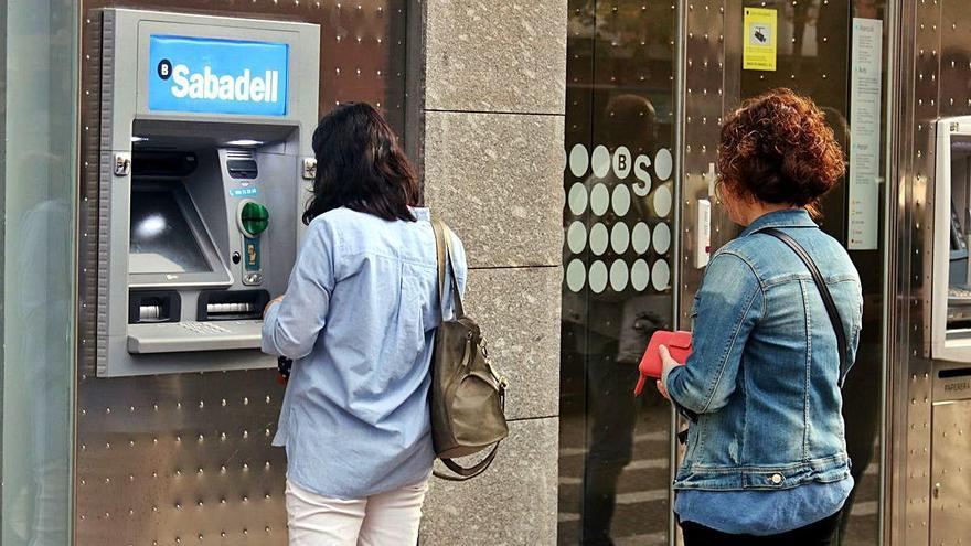 Dues usuàries treuen diners d&#039;un caixer de Banc Sabadell, en una imatge d&#039;arxiu.