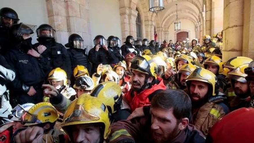 Agentes de los Mossos tratan de impedir que decenas de bomberos entren en el edificio del Parlament. // Efe