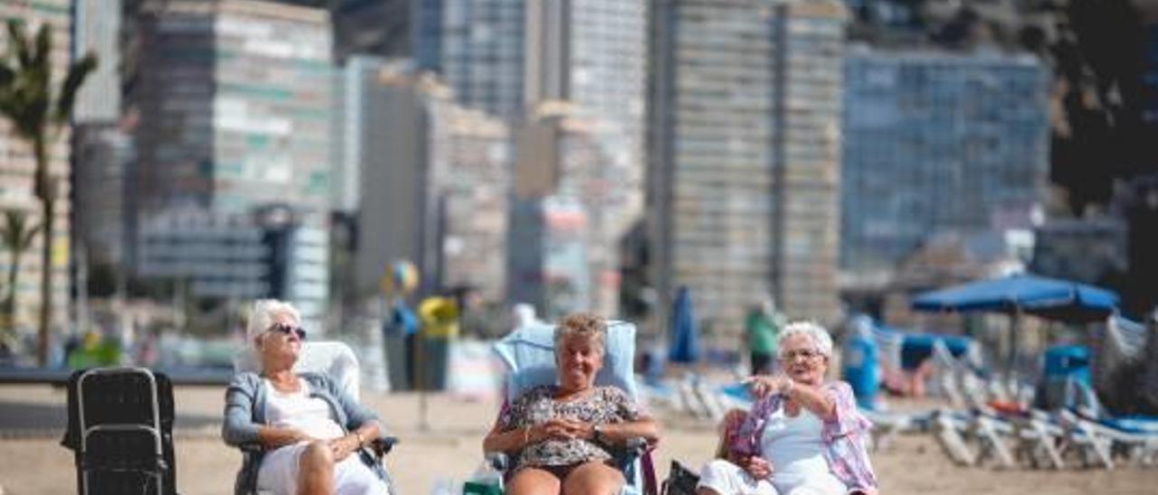 Tres turistas ayer en la playa de Benidorm disfrutando de la buena climatología.