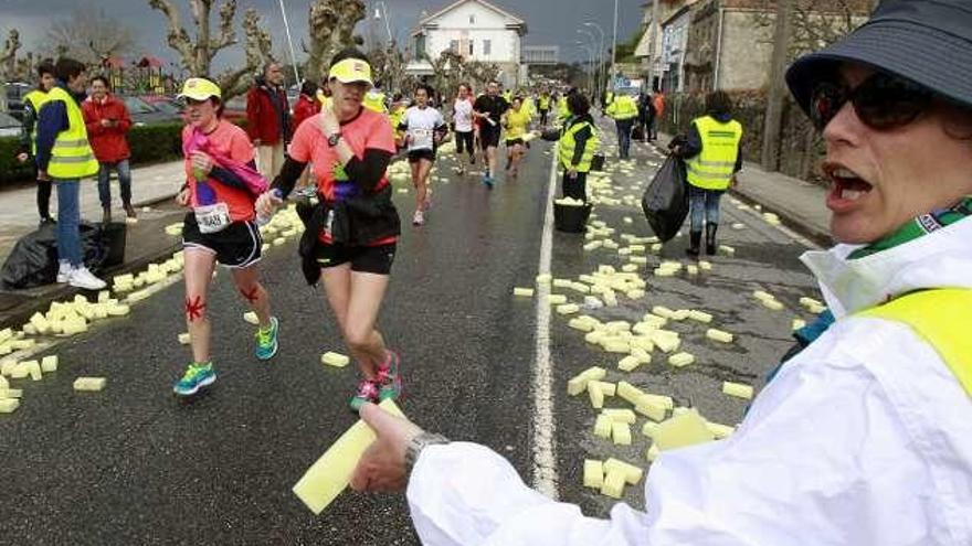 Voluntarios reparten esponjas en los avituallamientos. // J. Lores