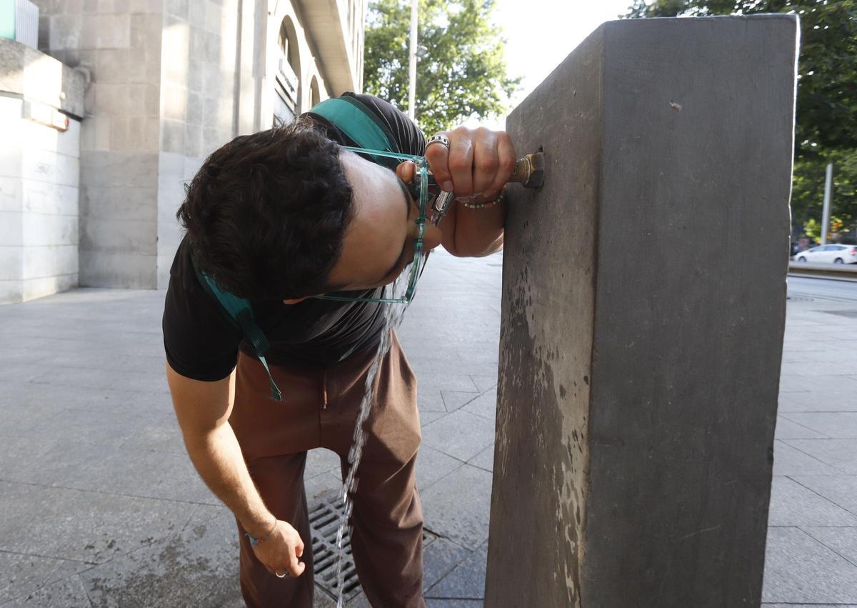 Un hombre bebe agua de una fuente pública en el centro de Zaragoza