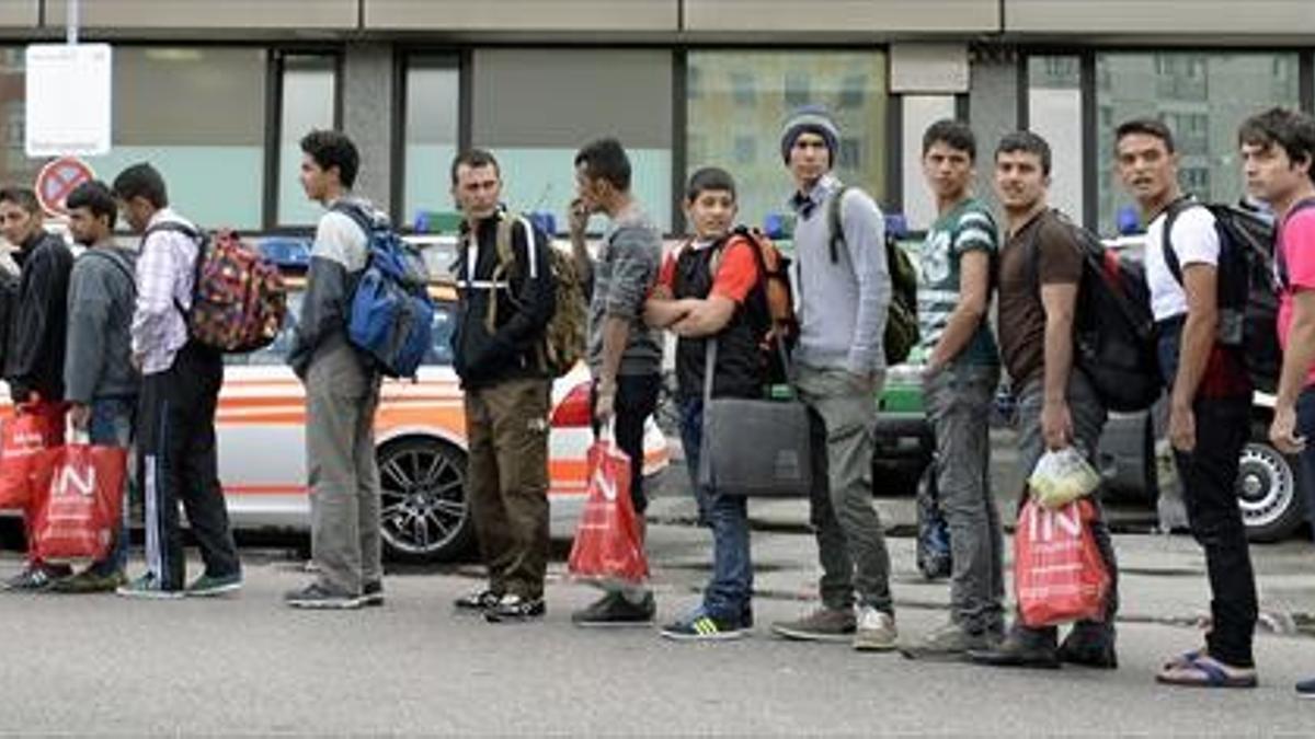 Los refugiados hacen cola para coger el autobús tras llegar ayer a la estación de trenes de Múnich.