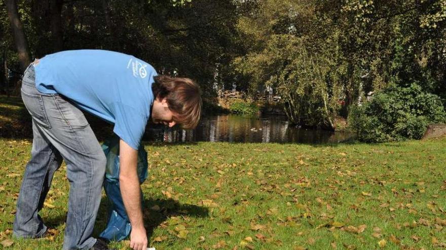 Un voluntario recoge un plástico en la orilla del río Bolaños en Arteixo. la opinión