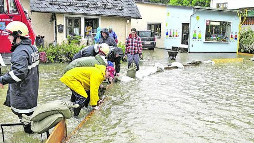 Bomberos y voluntarios echan sacos de arena en una calle de Mattighofen, cerca de Braunau (Austria).