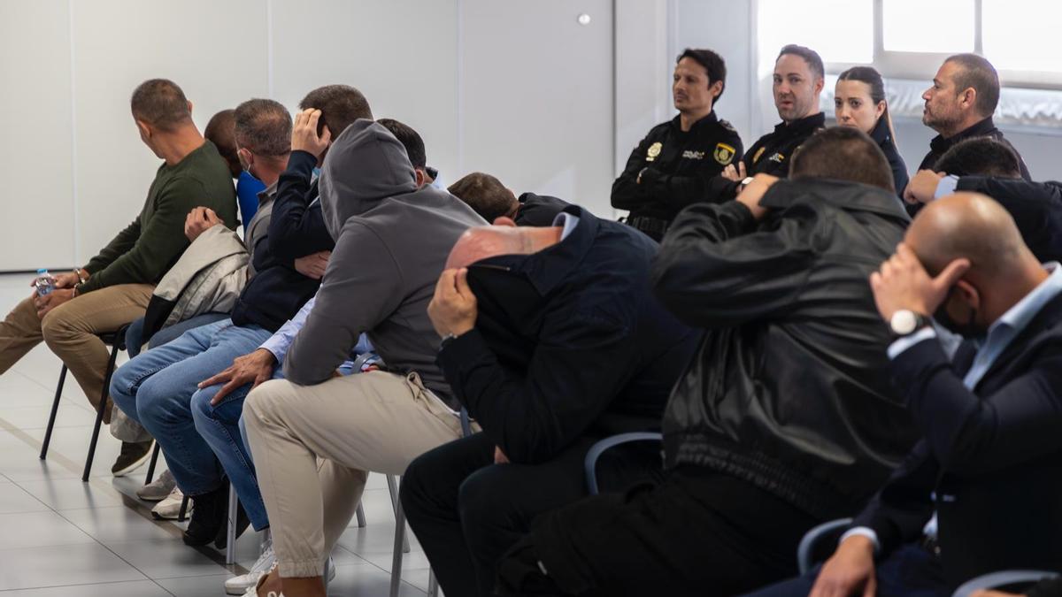 Los 14 acusados, ayer, ocultan sus rostros durante la primera sesión del juicio por la mensajería Sky.