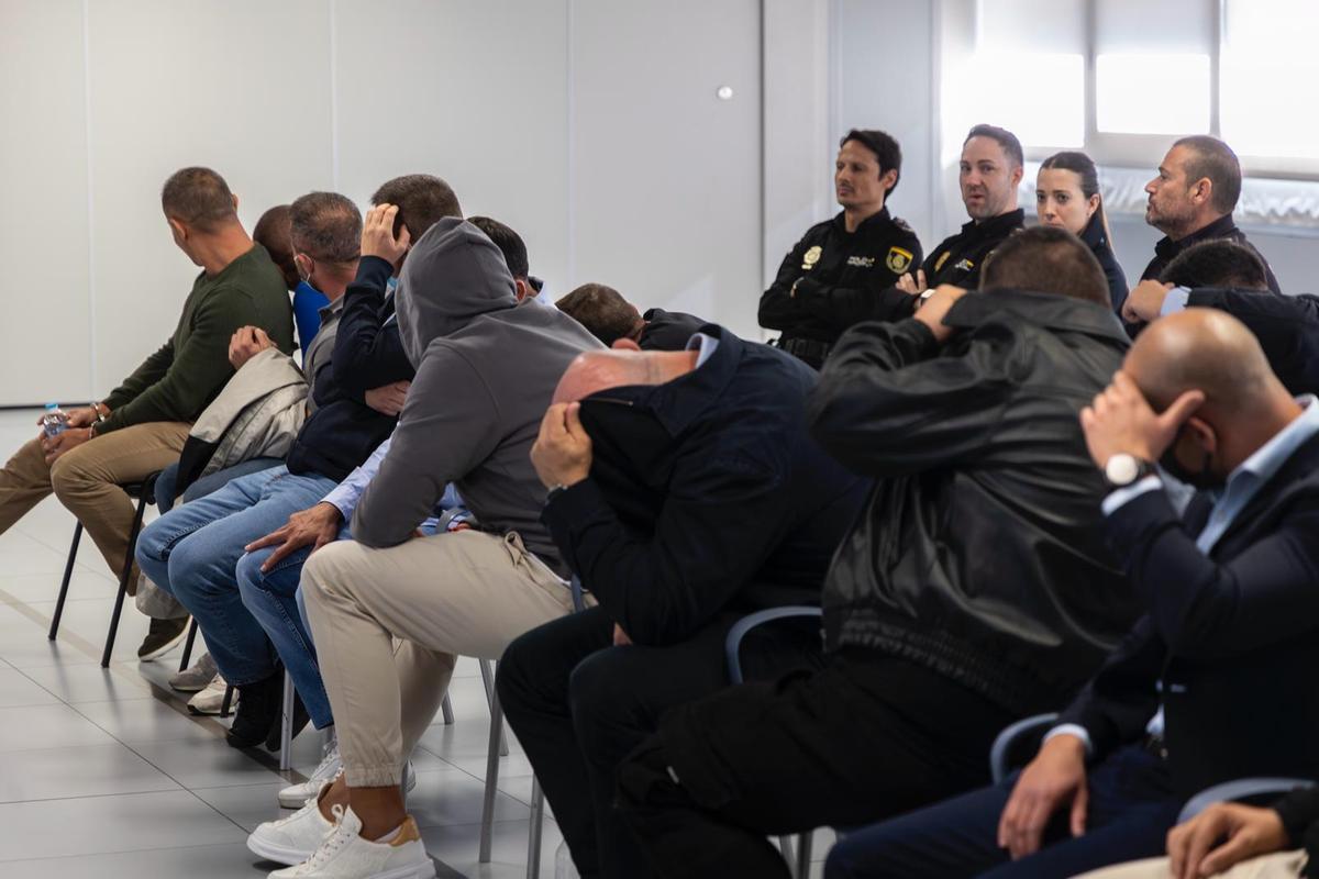 Los 14 acusados, ayer, ocultan sus rostros durante la primera sesión del juicio por la mensajería Sky.