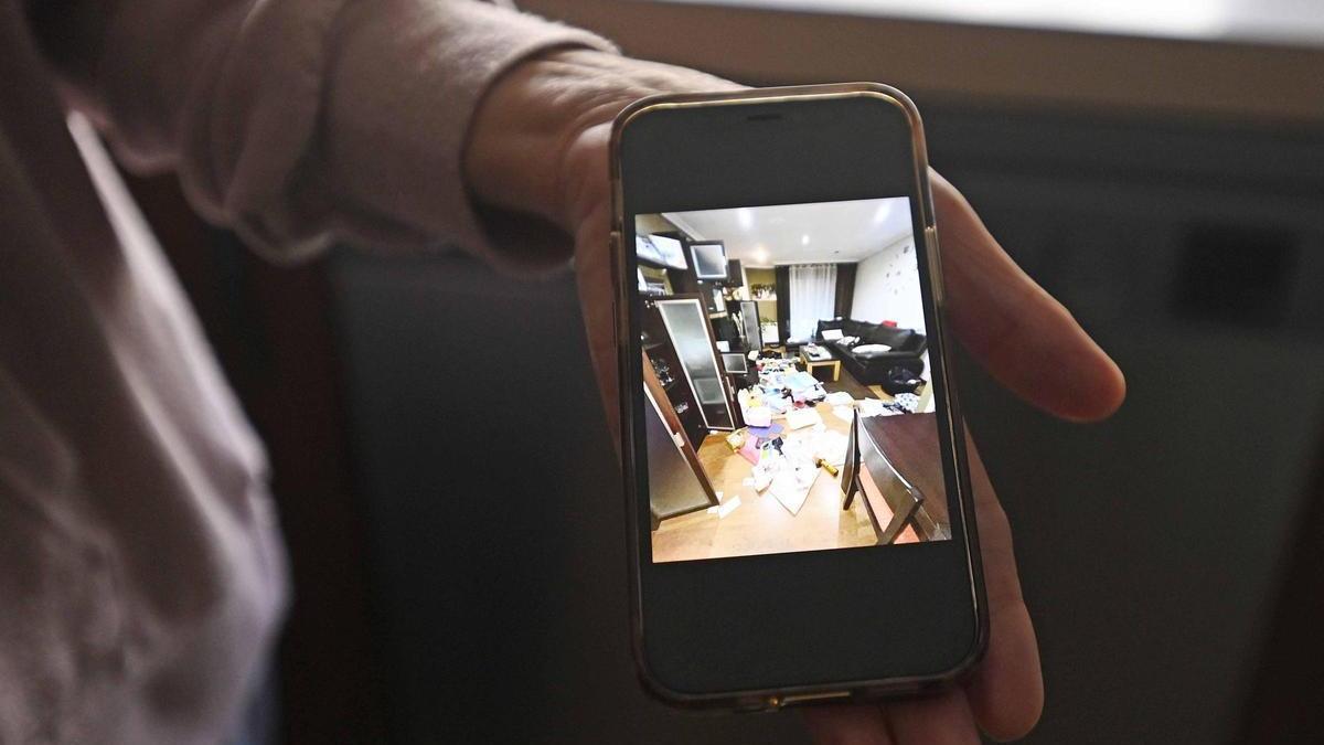 La mujer muestra una foto del estado del salón tras el robo.