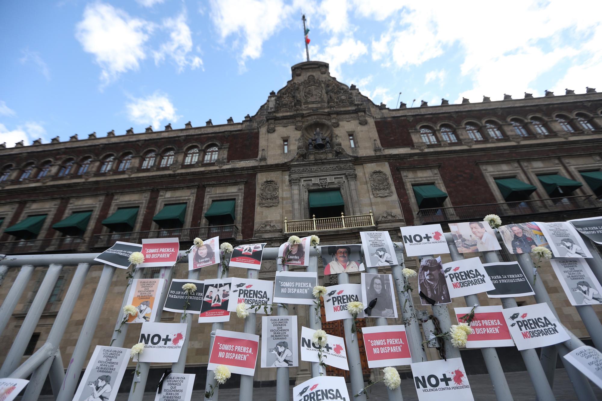 Fotografía de carteles y retratos en memoria de periodistas asesinados en el exterior de Palacio Nacional de Ciudad de México.