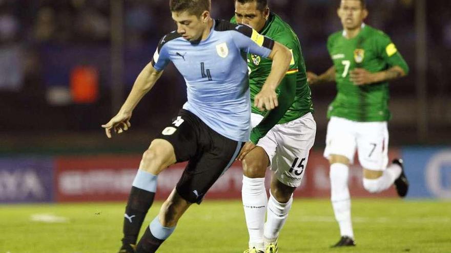 Valverde conduce el balón perseguido por dos futbolistas de Bolivia.