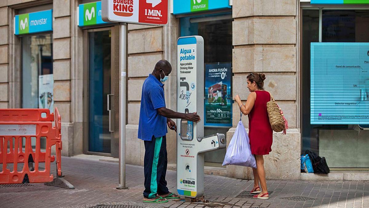 Un viandante se refresca en un punto de suministro de agua, en Palma.