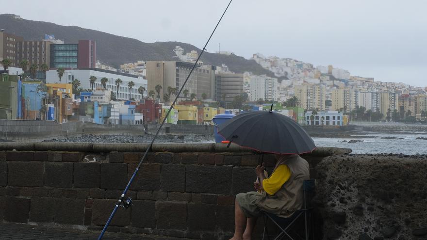 Un pescador se protege de la lluvia en San Cristobal