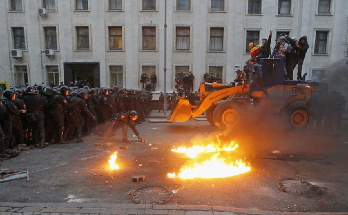 Unos manifestantes montan en una excavadora con la intención de romper con el muro policial.