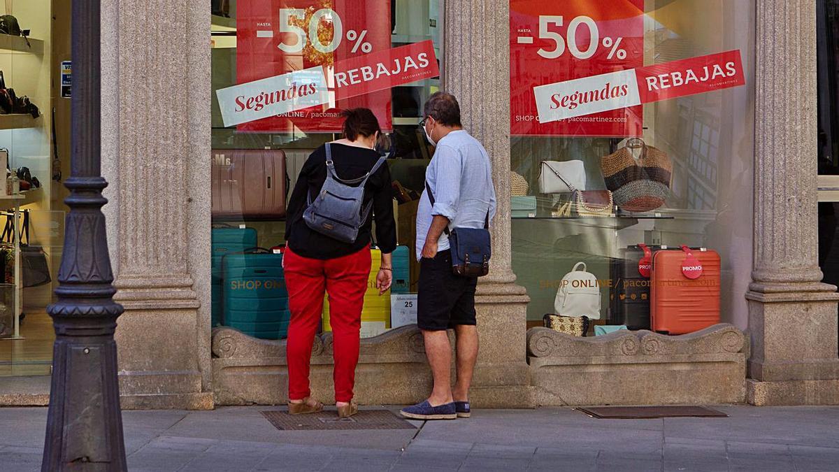 Dos personas curiosean en un escaparate de la ciudad.