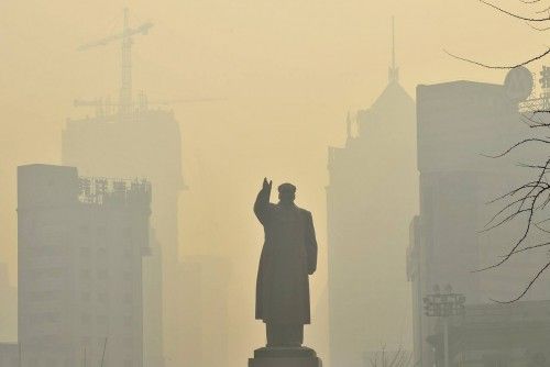 Una estatua de Mao Zedong se vislumbra entre los edificios durante un día neblinoso en Shenyang (China)