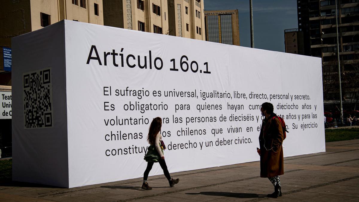 Dos personas pasan junto a una instalación con el artículo 160.1 de la nueva Constitución de Chile que debe votarse en referéndum el 4 de septiembre, esta semana en Santiago.