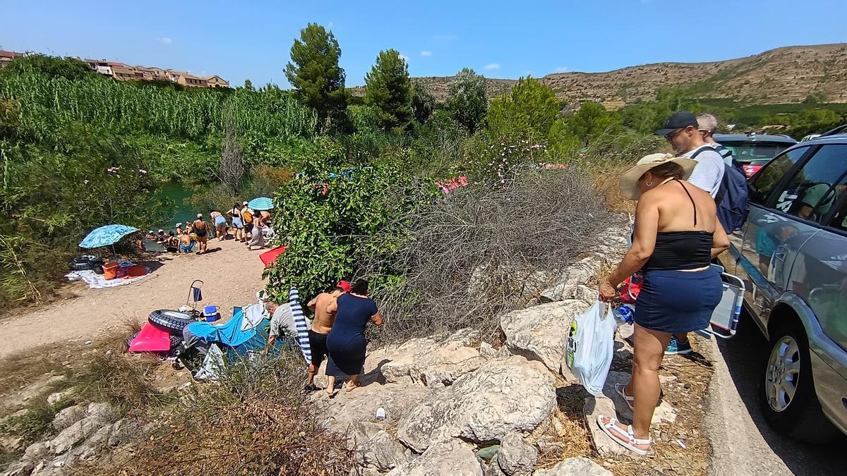 Visitantes acceden a través de las rocas a la orilla del Xúquer junto a la partida El Reguer de Antella.