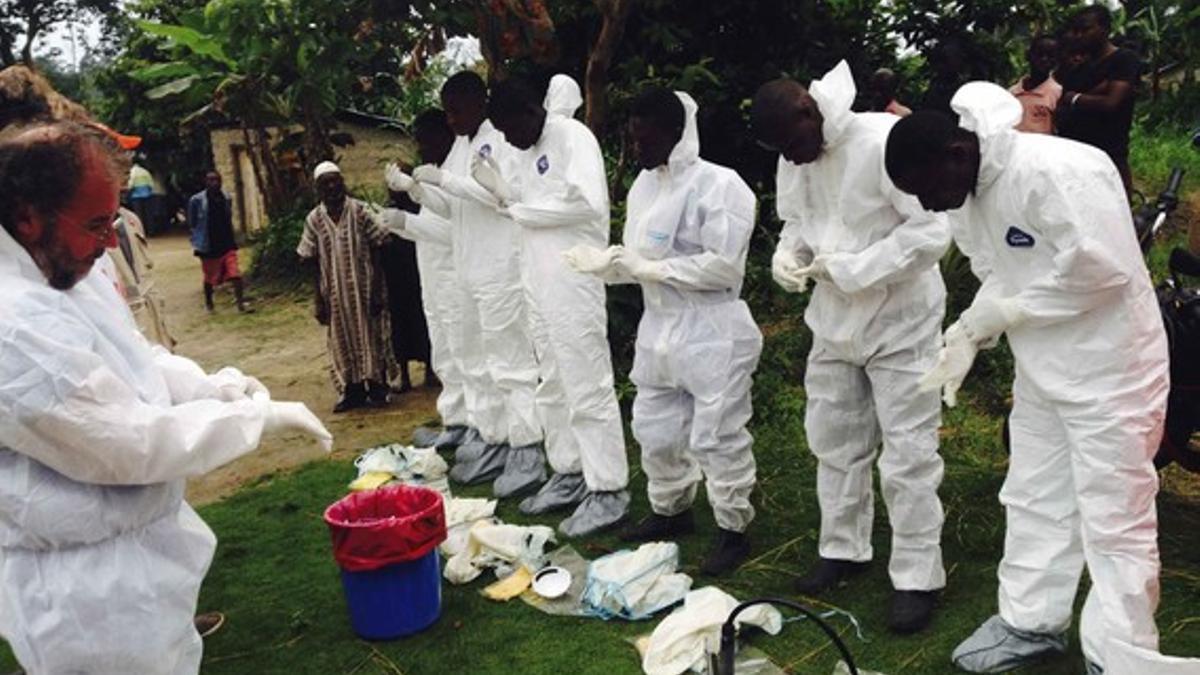 Voluntarios preparándose para ponerse los monos de aislamiento para tratar con enfermos de ébola, en Sierra Leona.