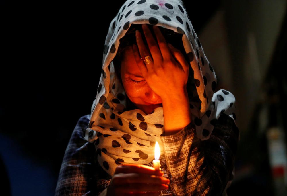 Una mujer llora mientras sostiene una vela encendida para las víctimas de la explosión del miércoles en Kabul, Afganistán. REUTERS.