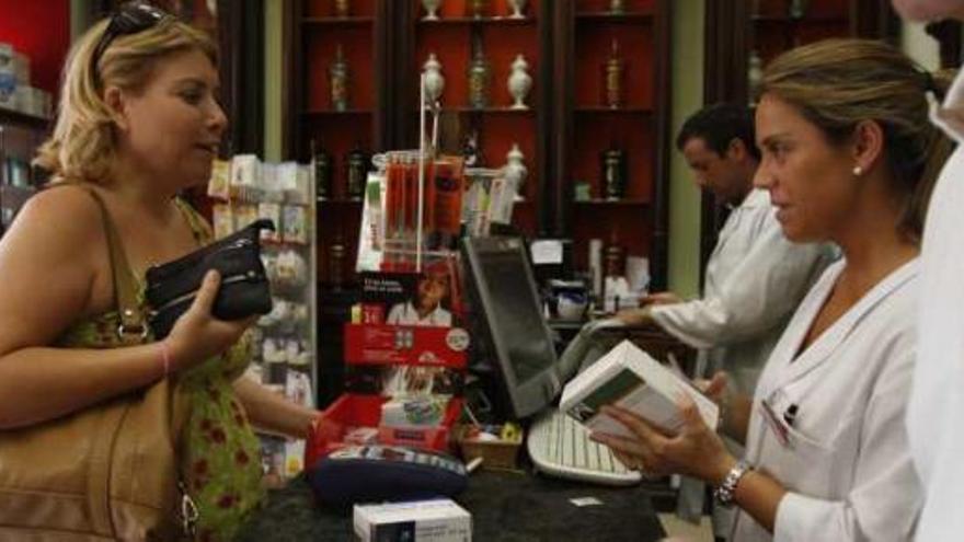 Una clientes compran ayer sus medicinas en una farmacia del Centro de Málaga.