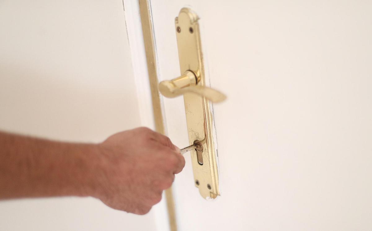 Archivo - Un hombre introduce una llave en la cerradura de la puerta de su nueva vivienda