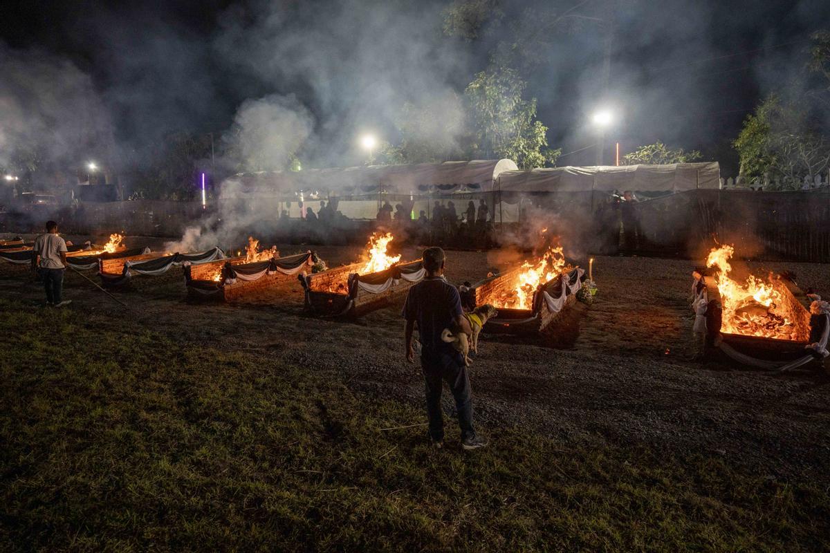 La gente observa cómo las piras funerarias incineran a 19 víctimas del tiroteo de la guardería Uthai Suwan en el templo Wat Rat Samakee 