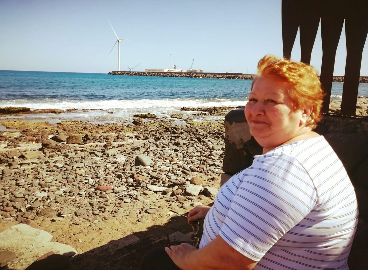 Última foto de Manoli hace un año, sonriente, sentada en una zona de la playa de Arinaga.