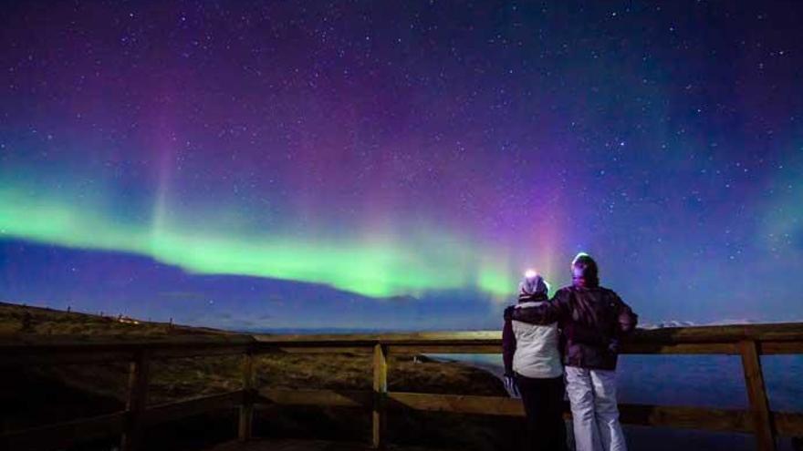 Una pareja disfruta de una aurora boreal.